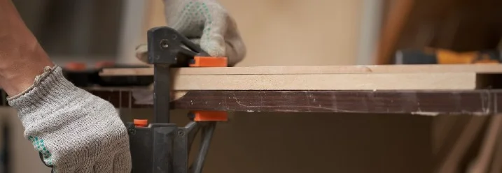 Person fixiert Holz mit Schraubzwinge